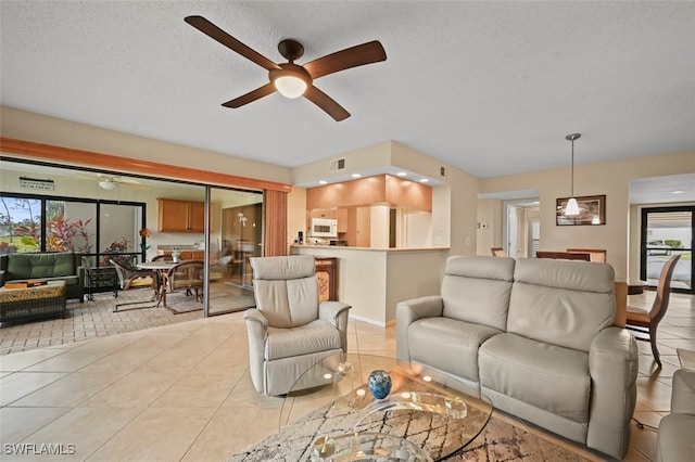 living room with ceiling fan, a textured ceiling, and light tile patterned flooring