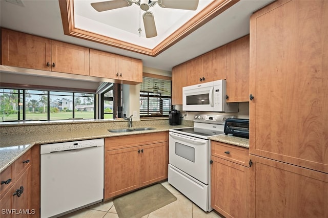 kitchen featuring white appliances, light stone countertops, light tile patterned floors, sink, and a raised ceiling