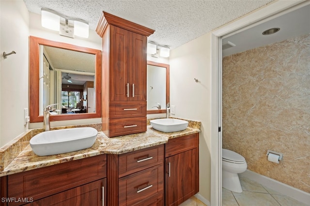 bathroom with a textured ceiling, toilet, tile patterned floors, and vanity