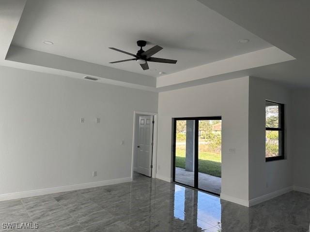 spare room with a raised ceiling and ceiling fan