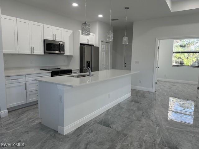 kitchen with a center island with sink, stainless steel appliances, white cabinetry, and pendant lighting