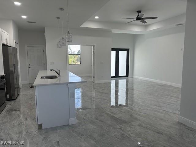 kitchen featuring sink, pendant lighting, stainless steel fridge with ice dispenser, white cabinets, and an island with sink