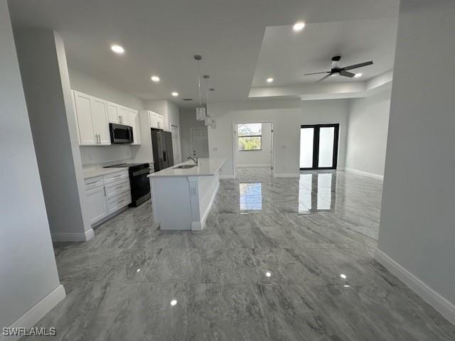 kitchen with a center island with sink, white cabinetry, a tray ceiling, black appliances, and hanging light fixtures