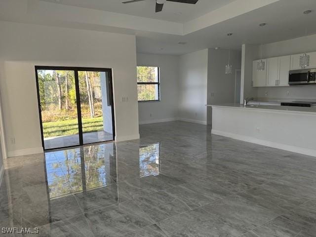 unfurnished living room featuring a tray ceiling and ceiling fan