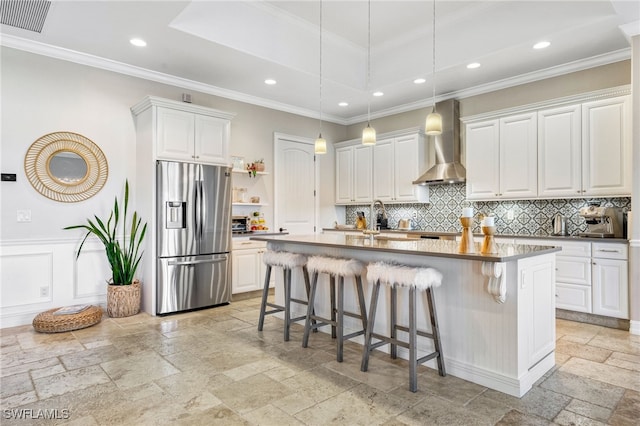 kitchen featuring an island with sink, a kitchen bar, stainless steel fridge with ice dispenser, and white cabinets