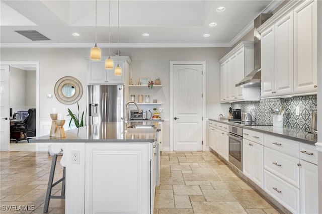 kitchen featuring hanging light fixtures, white cabinetry, appliances with stainless steel finishes, and a kitchen island with sink