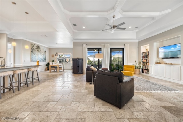 living room featuring ceiling fan, ornamental molding, and coffered ceiling