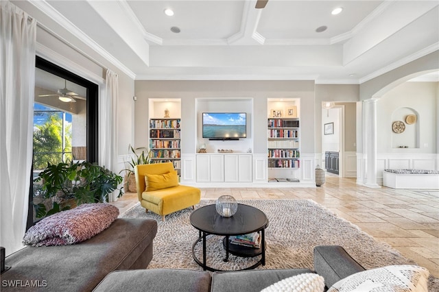 living room featuring crown molding, built in shelves, ceiling fan, and ornate columns