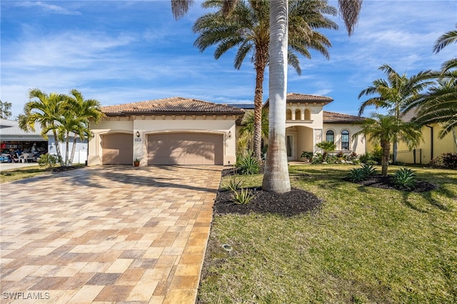 mediterranean / spanish-style home with a garage and a front lawn