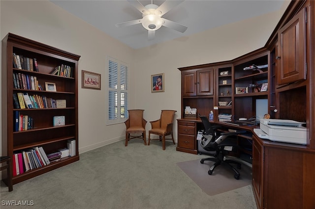 office area with a ceiling fan, baseboards, and light colored carpet