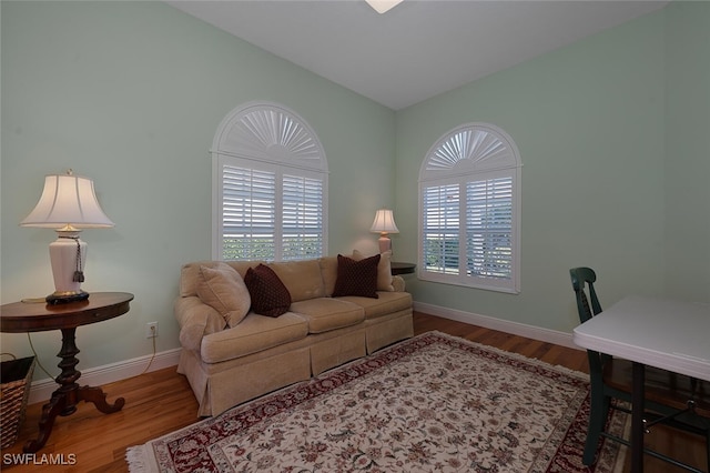 living room with baseboards, lofted ceiling, wood finished floors, and a healthy amount of sunlight