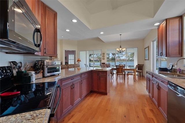 kitchen featuring a sink, a peninsula, light wood-style flooring, black appliances, and recessed lighting