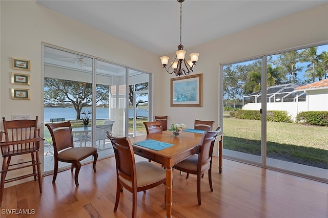 dining space with a water view, an inviting chandelier, and light hardwood / wood-style floors