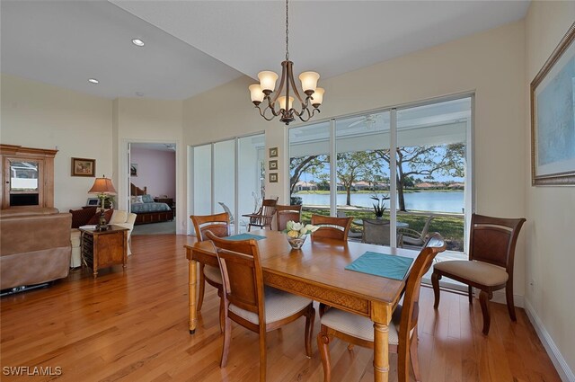 dining room with an inviting chandelier, light hardwood / wood-style flooring, and a water view