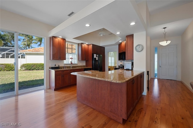 kitchen featuring sink, light hardwood / wood-style flooring, hanging light fixtures, kitchen peninsula, and black appliances