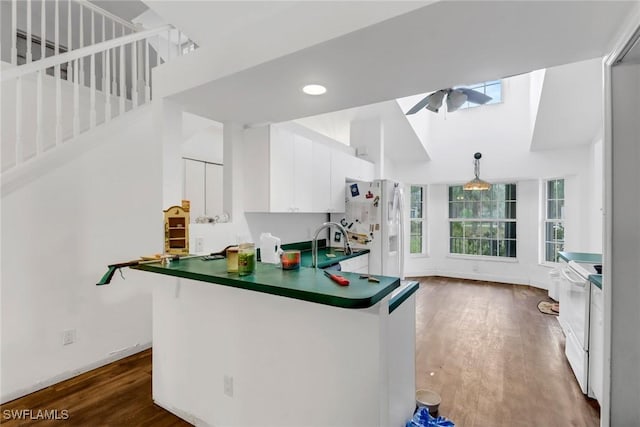 kitchen featuring sink, dark hardwood / wood-style floors, kitchen peninsula, white appliances, and white cabinets