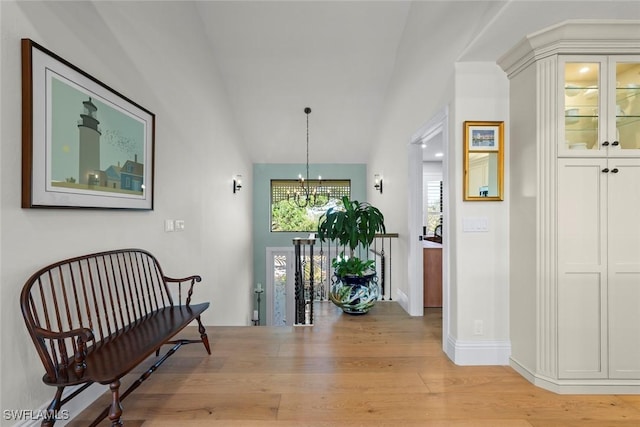 interior space with a chandelier, vaulted ceiling, and light wood-style floors