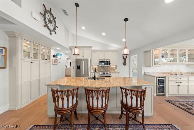 kitchen with glass insert cabinets, beverage cooler, white cabinets, and appliances with stainless steel finishes