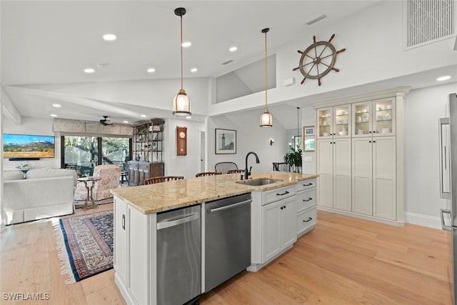 kitchen featuring a center island with sink, stainless steel dishwasher, open floor plan, white cabinetry, and a sink