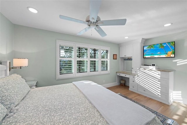 bedroom with light wood-type flooring, ceiling fan, built in desk, and recessed lighting