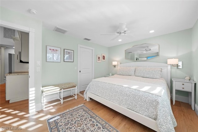 bedroom featuring light wood finished floors, visible vents, and a ceiling fan