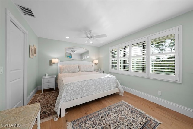 bedroom with a ceiling fan, baseboards, visible vents, and wood finished floors