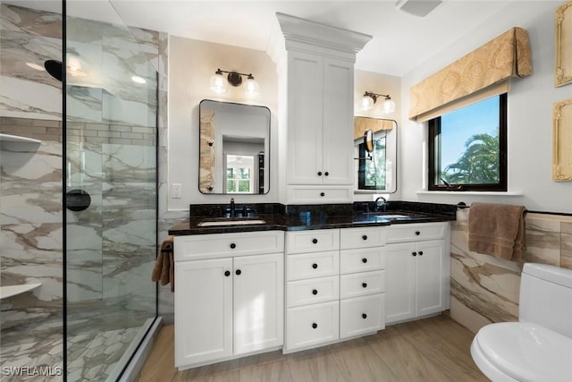 bathroom with a sink, tile walls, a marble finish shower, and double vanity