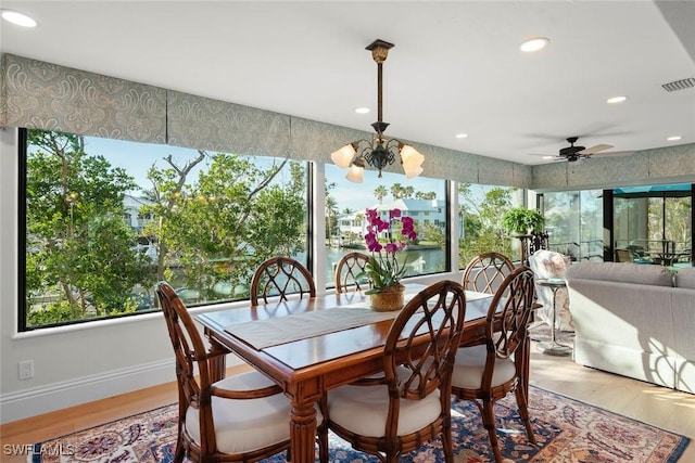 dining space with visible vents, a water view, baseboards, and wood finished floors