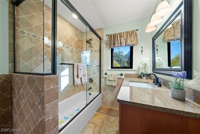 bathroom featuring tile walls, vanity, and bath / shower combo with glass door