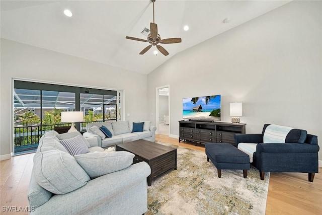 living room with ceiling fan, high vaulted ceiling, and light hardwood / wood-style flooring