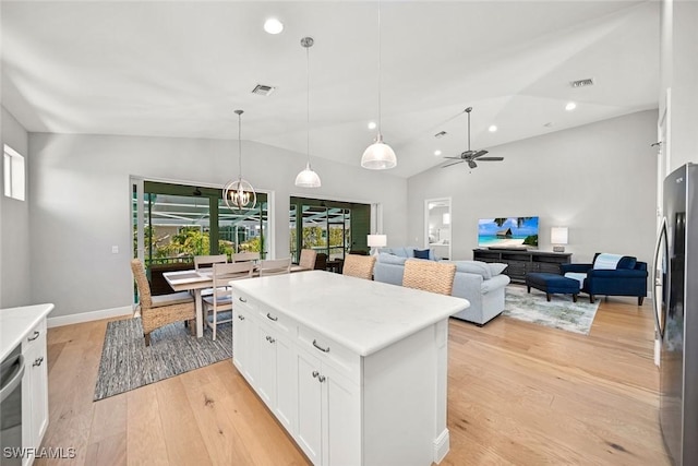 kitchen featuring white cabinetry, stainless steel fridge, decorative light fixtures, lofted ceiling, and a center island