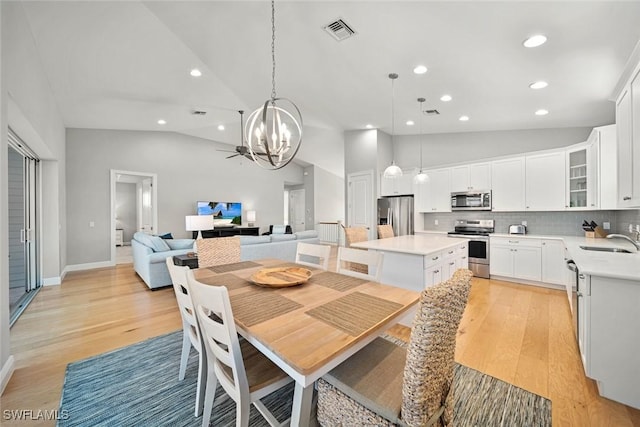 dining area with vaulted ceiling, a chandelier, light wood-type flooring, and sink