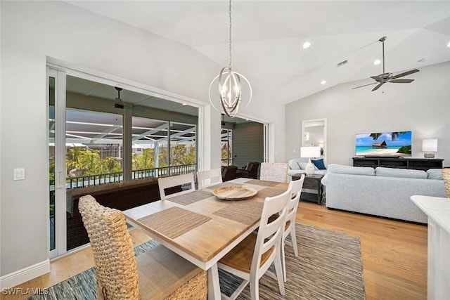 dining space with light wood-type flooring, lofted ceiling, and ceiling fan with notable chandelier