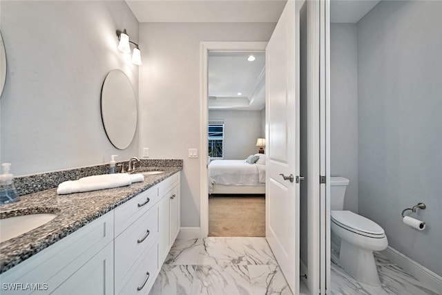 bathroom with toilet, ornamental molding, a tray ceiling, and vanity