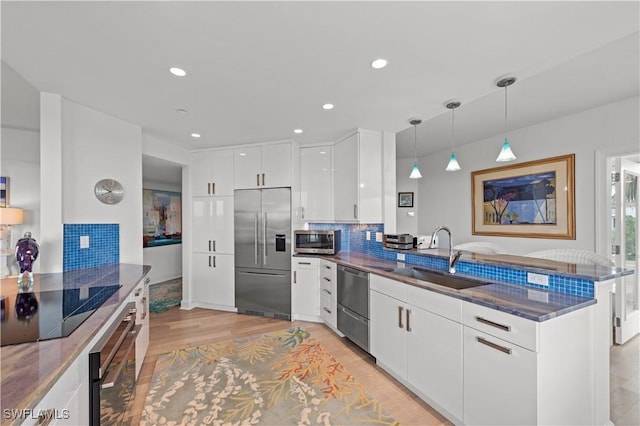 kitchen featuring kitchen peninsula, decorative light fixtures, sink, white cabinets, and black appliances