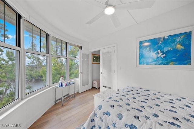 bedroom featuring ceiling fan, a water view, and light hardwood / wood-style floors