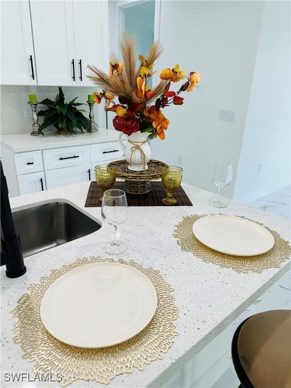 interior details featuring light stone countertops and white cabinets