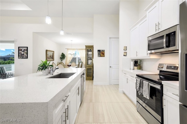 kitchen featuring pendant lighting, white cabinetry, sink, a kitchen island with sink, and stainless steel appliances