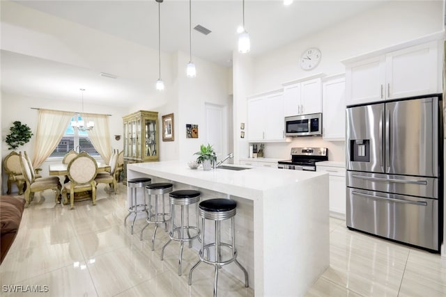 kitchen with stainless steel appliances, decorative light fixtures, an island with sink, and light tile patterned floors