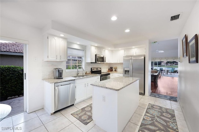 kitchen with a center island, white cabinetry, light tile patterned floors, sink, and stainless steel appliances