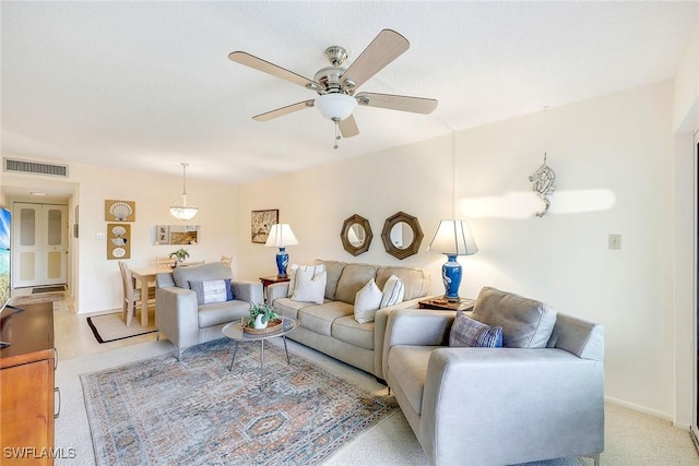 living area with light carpet, visible vents, baseboards, and ceiling fan