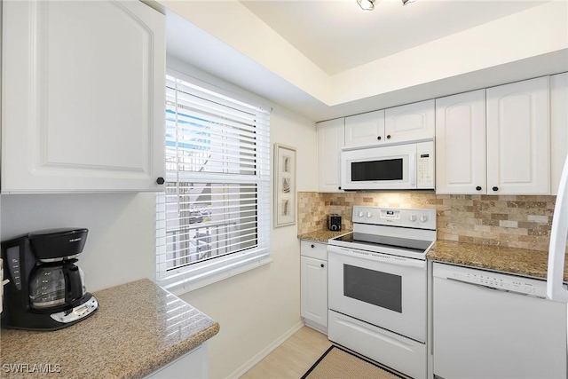 kitchen with decorative backsplash, white appliances, light stone countertops, and white cabinetry