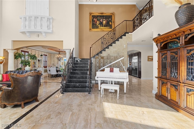 foyer entrance featuring crown molding, a chandelier, and a high ceiling