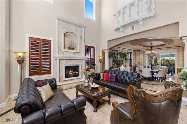 living room with an inviting chandelier, a fireplace, plenty of natural light, and ornate columns