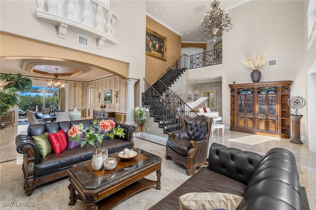 living room featuring an inviting chandelier, a towering ceiling, crown molding, and decorative columns