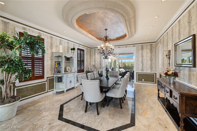 dining area featuring a raised ceiling, ornamental molding, and a chandelier