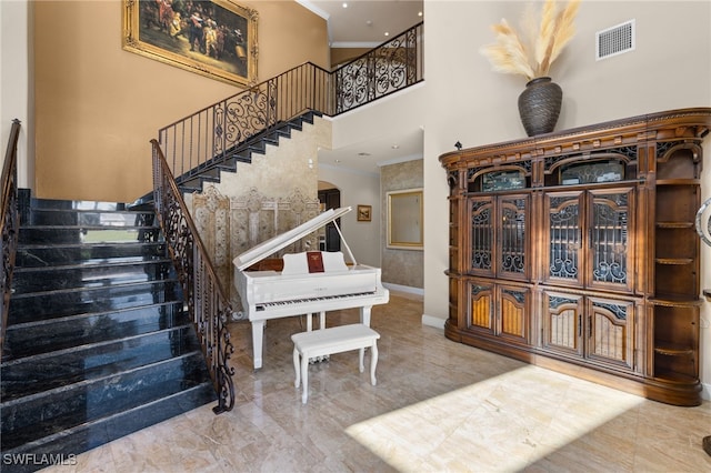 staircase featuring crown molding and a towering ceiling