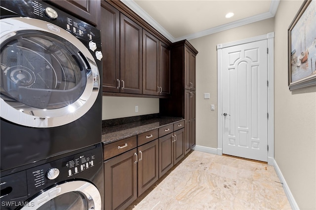 clothes washing area featuring cabinets, stacked washer / dryer, and ornamental molding