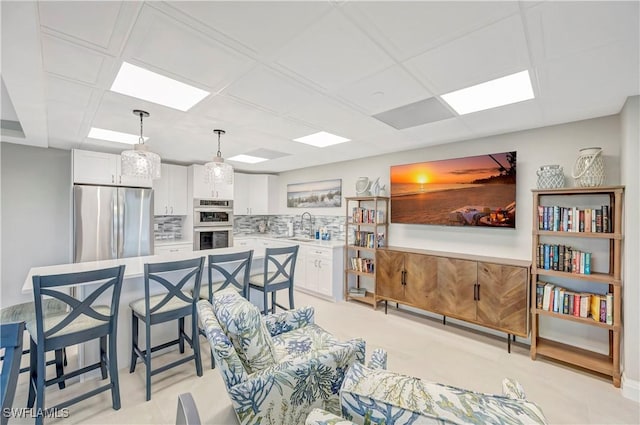 kitchen with sink, a breakfast bar, hanging light fixtures, stainless steel appliances, and white cabinets