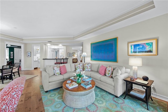 living room featuring ornamental molding, hardwood / wood-style floors, and a raised ceiling